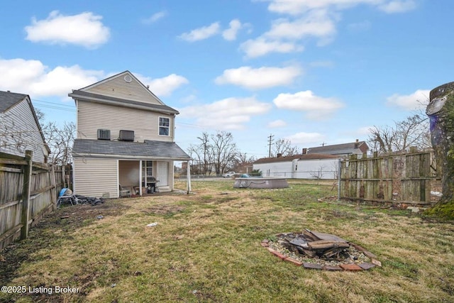 back of house with a yard and a fenced backyard