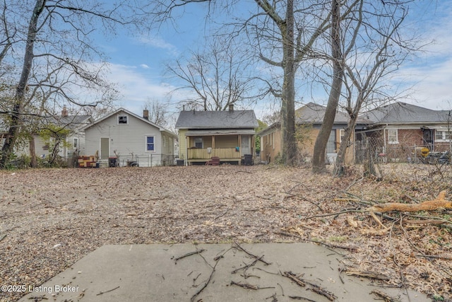 rear view of property with covered porch and fence