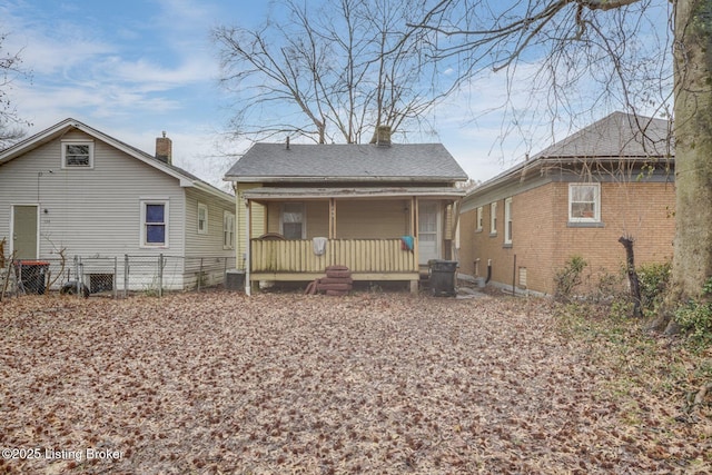 rear view of property featuring fence, a porch, and roof with shingles