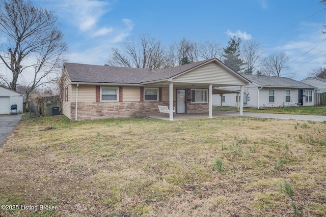 single story home with cooling unit, stone siding, driveway, a carport, and a front yard