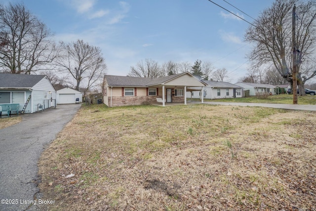 view of front of home with covered porch, a front yard, a detached garage, and an outbuilding