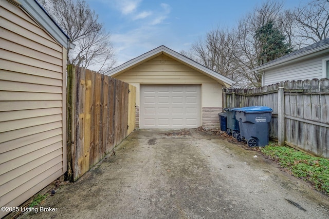 detached garage with concrete driveway and fence