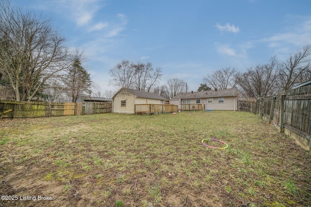 view of yard with an outbuilding, a fenced backyard, and a wooden deck