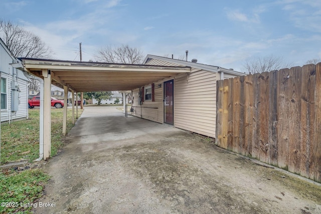 view of parking featuring a carport, fence, and concrete driveway