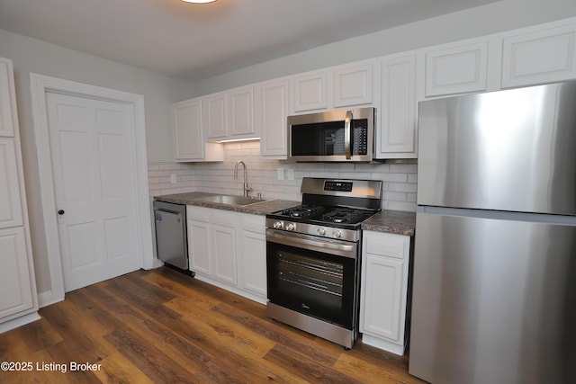 kitchen featuring white cabinetry, stainless steel appliances, sink, backsplash, and dark wood-type flooring