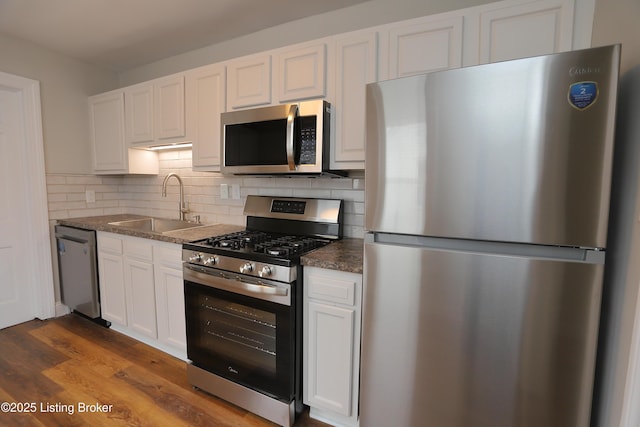 kitchen featuring appliances with stainless steel finishes, decorative backsplash, sink, and white cabinets