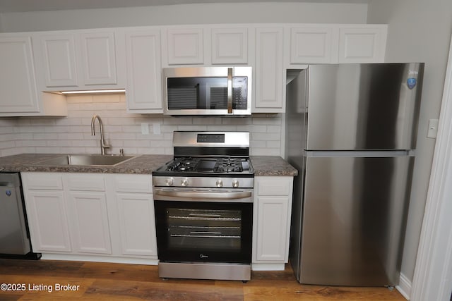 kitchen with stainless steel appliances, sink, white cabinets, dark hardwood / wood-style floors, and decorative backsplash