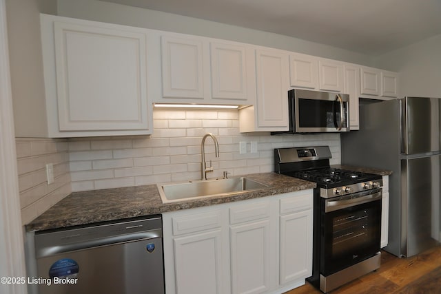 kitchen with sink, appliances with stainless steel finishes, white cabinetry, and tasteful backsplash