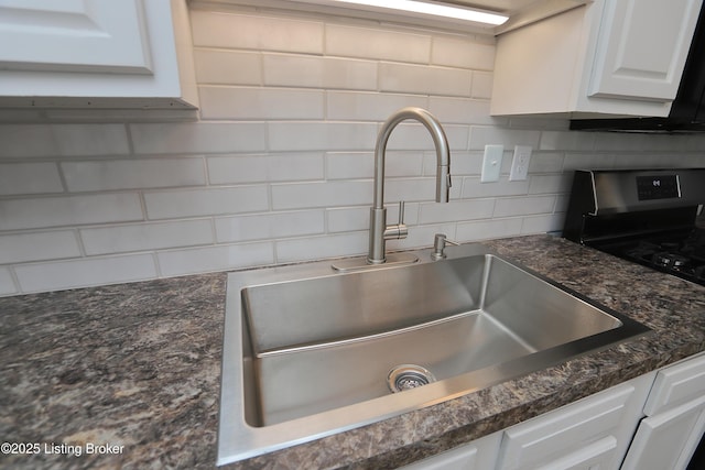 interior details featuring white cabinetry, sink, stainless steel range, and decorative backsplash