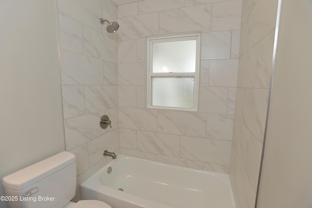 bathroom featuring tiled shower / bath combo and toilet