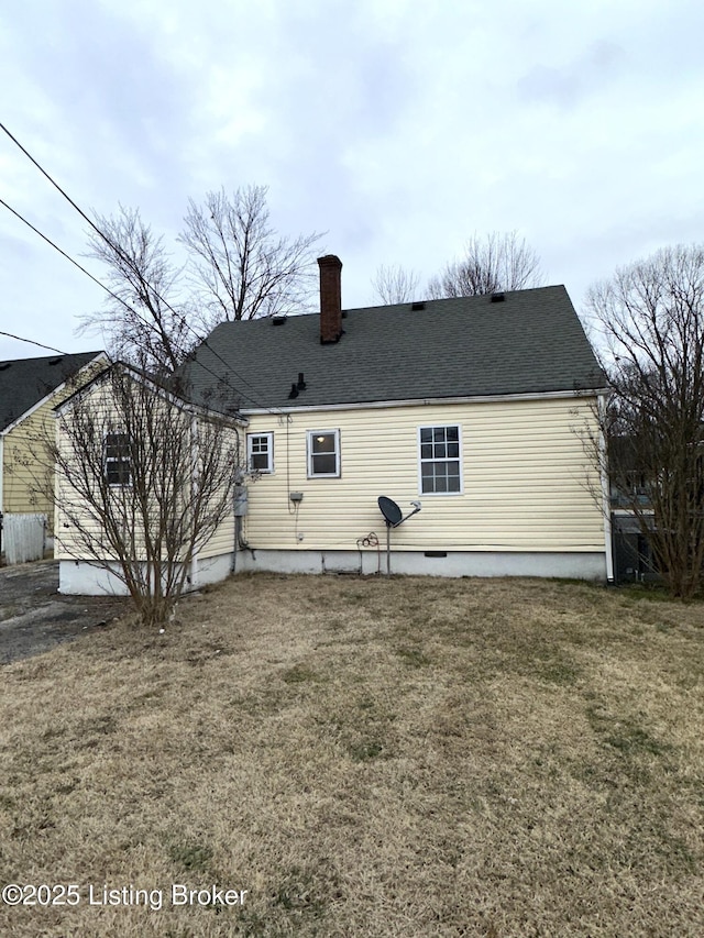 back of property featuring a shingled roof, a yard, and a chimney