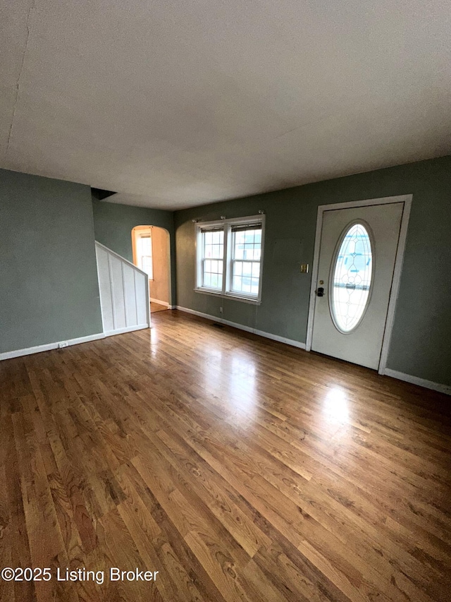 interior space featuring baseboards, arched walkways, and wood finished floors