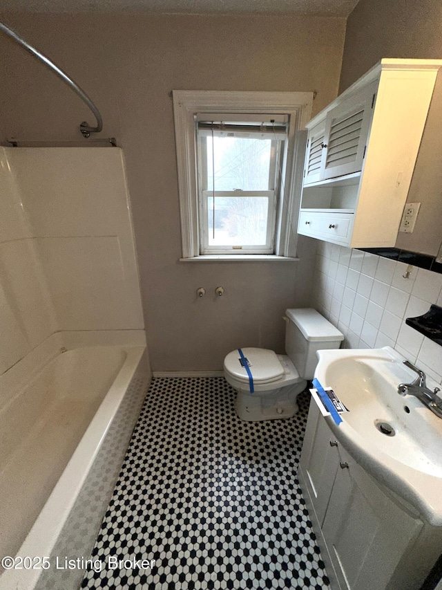 bathroom featuring toilet, bathing tub / shower combination, tile walls, and vanity