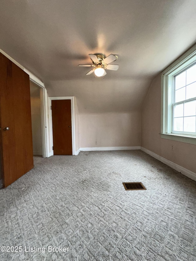 additional living space featuring visible vents, a ceiling fan, vaulted ceiling, baseboards, and carpet