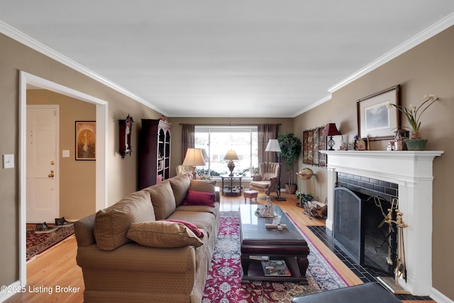 living room with ornamental molding, wood-type flooring, and a tiled fireplace