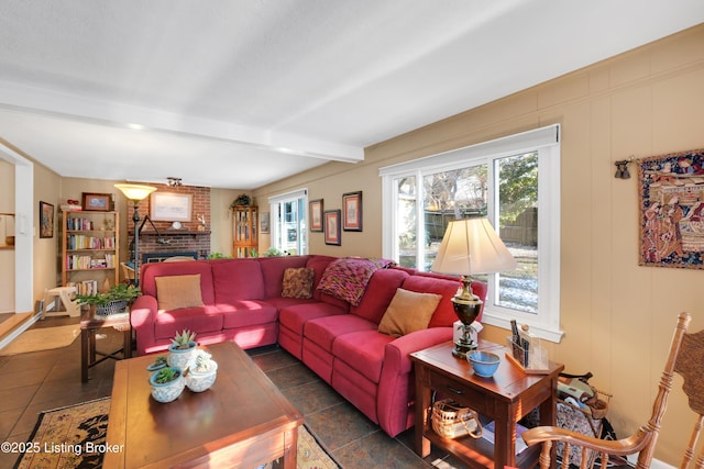 tiled living room featuring beamed ceiling, a brick fireplace, and a healthy amount of sunlight