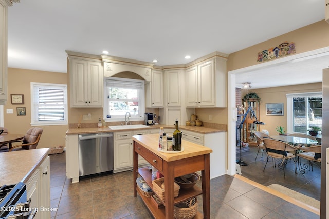 kitchen with stainless steel dishwasher, sink, cream cabinetry, and a wealth of natural light