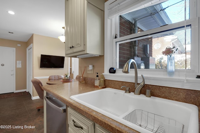 kitchen featuring stainless steel dishwasher, sink, dark tile patterned flooring, and cream cabinets