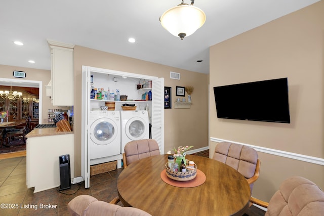 tiled dining space featuring a notable chandelier and washer and clothes dryer