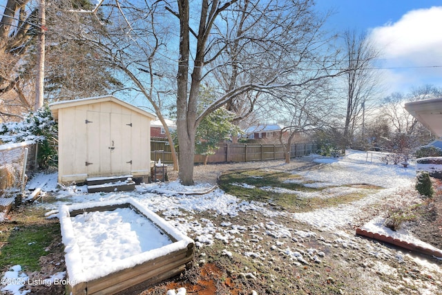 snowy yard featuring a storage unit