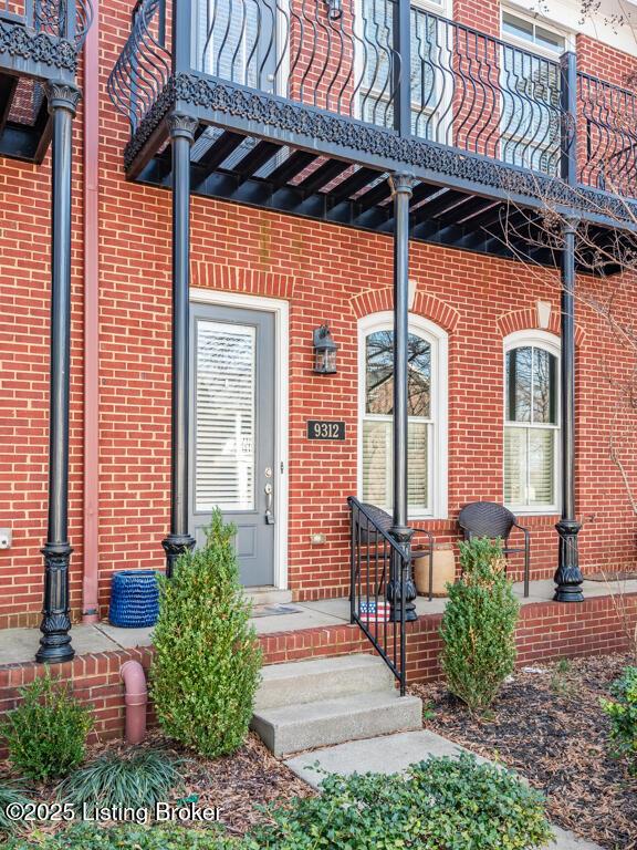 doorway to property with brick siding and a balcony