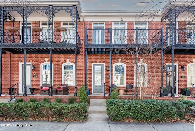 view of front of house featuring brick siding and a balcony