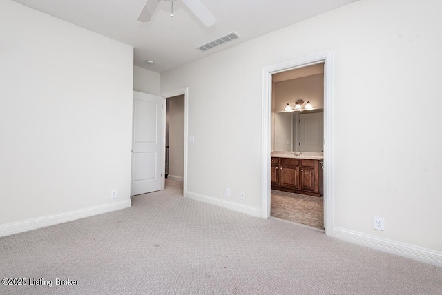 unfurnished bedroom with visible vents, light carpet, a sink, ensuite bath, and baseboards