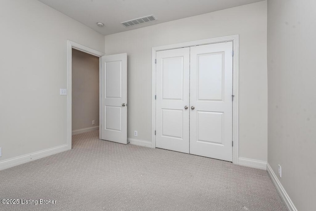 unfurnished bedroom with baseboards, a closet, visible vents, and light colored carpet