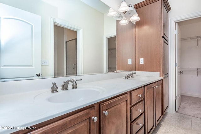 bathroom with double vanity, a stall shower, a sink, and an inviting chandelier