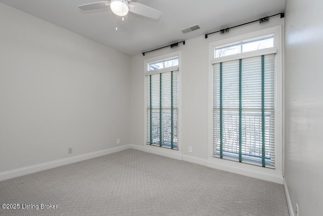 carpeted spare room featuring visible vents, ceiling fan, and baseboards