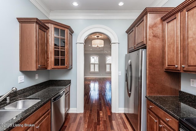 kitchen with glass insert cabinets, appliances with stainless steel finishes, arched walkways, and ornamental molding