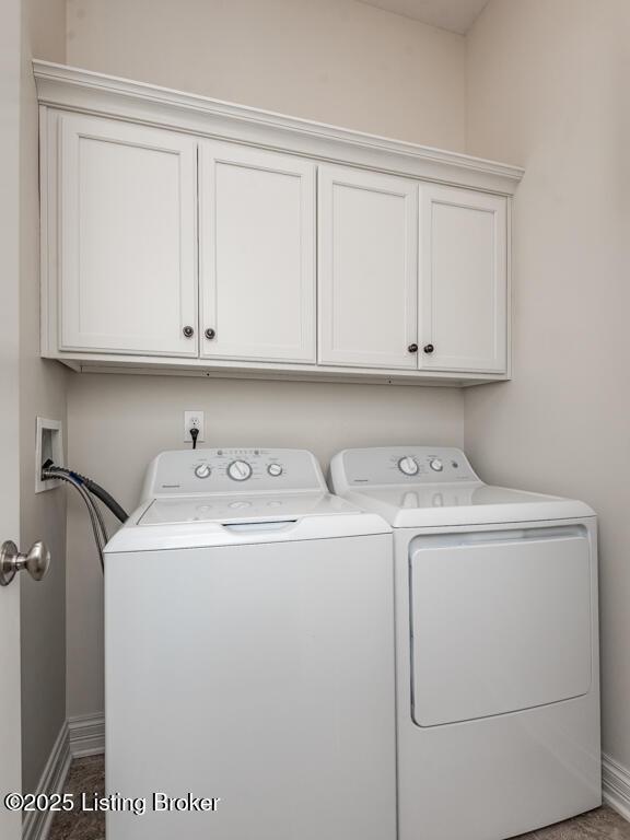 washroom with washer and dryer, cabinet space, and baseboards