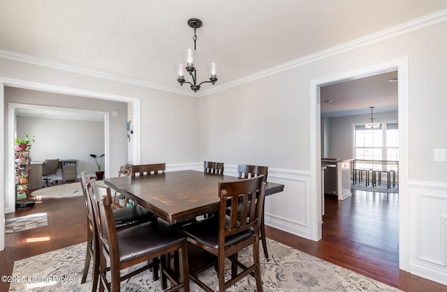 dining room with an inviting chandelier, ornamental molding, hardwood / wood-style floors, and wainscoting