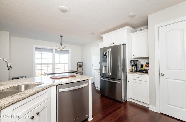 kitchen featuring a sink, white cabinets, appliances with stainless steel finishes, light stone countertops, and dark wood finished floors