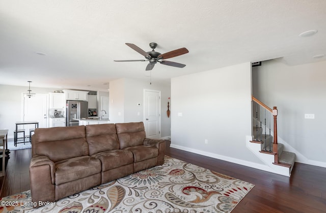 living room with baseboards, ceiling fan, stairway, dark wood-style flooring, and a textured ceiling