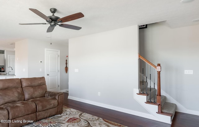 living room featuring dark wood-style floors, ceiling fan, stairway, and baseboards