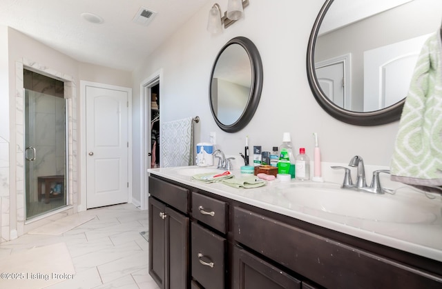 full bath featuring marble finish floor, a sink, visible vents, and a shower stall