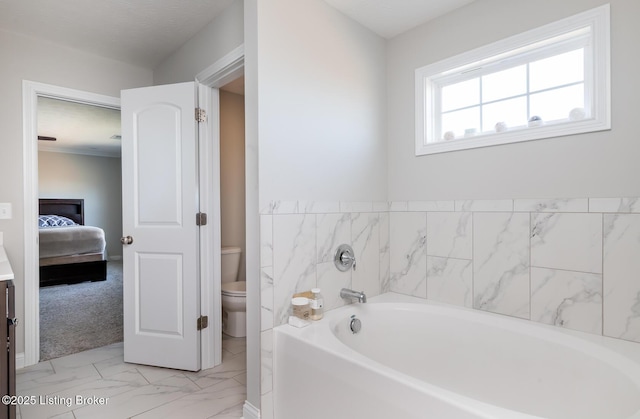 ensuite bathroom with marble finish floor, ensuite bath, toilet, and a bath