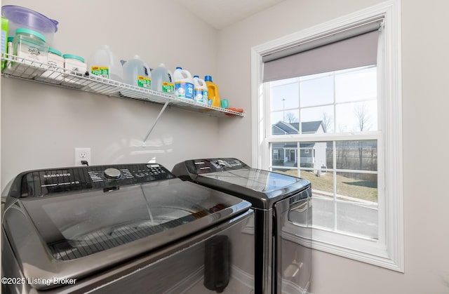 clothes washing area with laundry area, plenty of natural light, and washer and clothes dryer