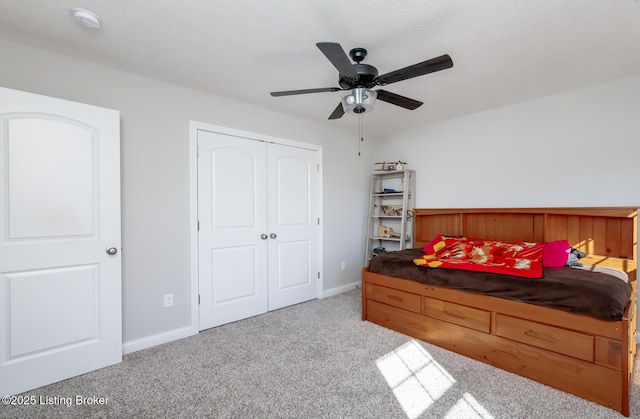 carpeted bedroom featuring a ceiling fan, a closet, a textured ceiling, and baseboards