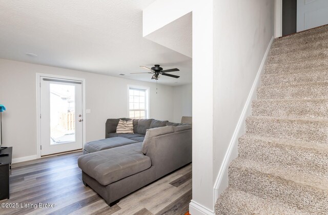 living room with baseboards, stairway, ceiling fan, and wood finished floors