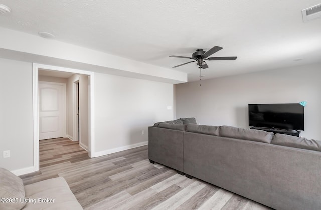 living room featuring visible vents, light wood-style flooring, and a textured ceiling