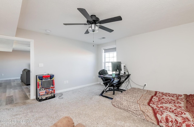 carpeted office space featuring visible vents, ceiling fan, a textured ceiling, and baseboards