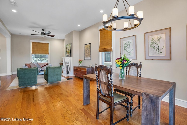 dining space with ceiling fan with notable chandelier and light hardwood / wood-style flooring