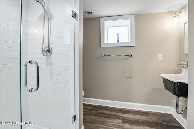 bathroom with wood-type flooring, toilet, and a shower with door