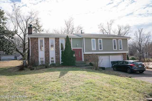 raised ranch featuring a garage, driveway, a chimney, and brick siding