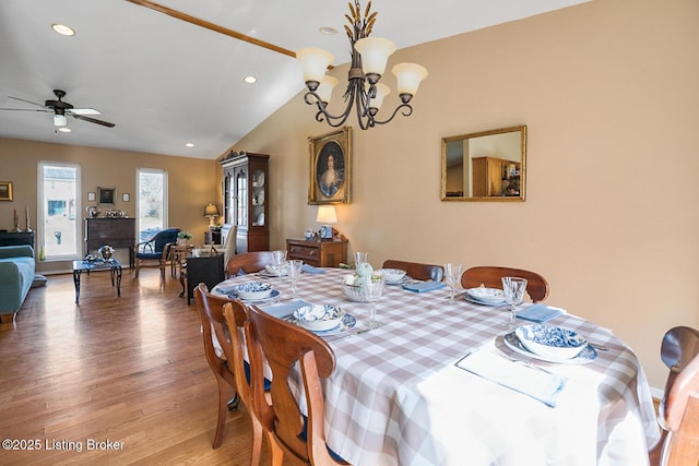 dining room with vaulted ceiling, ceiling fan with notable chandelier, wood finished floors, and recessed lighting