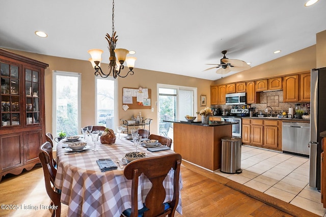 dining space with ceiling fan with notable chandelier, lofted ceiling, light wood finished floors, and recessed lighting