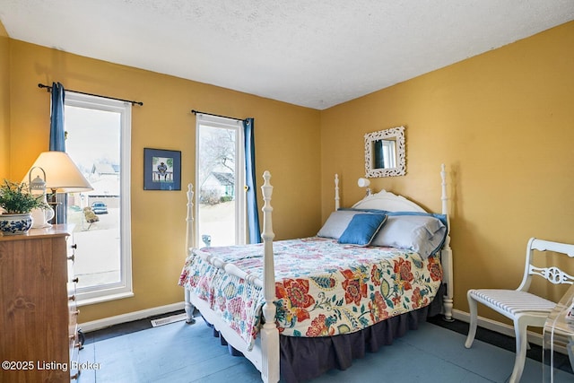 bedroom with access to exterior, a textured ceiling, and baseboards