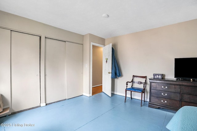 bedroom featuring baseboards, concrete floors, and multiple closets